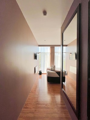 Ein modernes Hotelzimmer mit einem großen Spiegel, einem Bett, einem kleinen Tisch und einem Fenster mit Vorhängen.