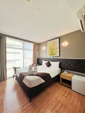 A modern hotel room with a large bed, a desk, a chair, and a window with curtains. - Cebu Capitol Central Hotel and Suites Powered by Cocotel (Cebu City)