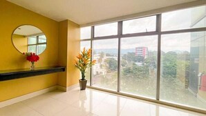 Ein Hotelzimmer mit großem Fenster, rundem Spiegel und Topfpflanze.