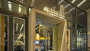 A modern hotel entrance with a concierge desk, glass doors, and a well-lit interior.
