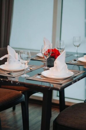 A dining table set with white napkins, wine glasses, and a centerpiece of red flowers. - Bertam Resort & Water Park (Kepala Batas)