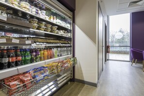 Un pasillo de un supermercado con estantes llenos de diversos alimentos y bebidas.