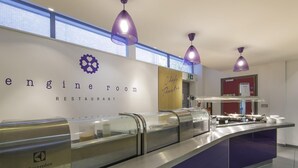 Zona de bufé con un cartel en la pared que dice 'Restaurante Timonel' y 'Teatro de Chefs'.