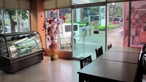A restaurant interior with a glass display case, a dining table, and chairs. - Oftana Suites (Mandaue)
