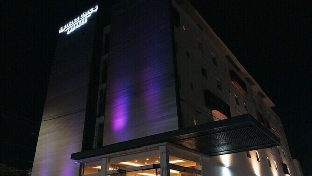 A modern hotel with a prominent sign, large windows, and a covered entrance area. - Eco Express Hotel Poliforum (León)