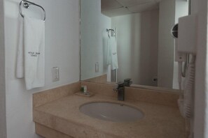 A bathroom with a sink, mirror, towel rack, and a hairdryer. - Eco Express Hotel Poliforum (León)