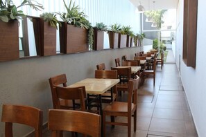 A restaurant with wooden tables and chairs, a long counter, and vertical planters with greenery. - Eco Express Hotel Poliforum (León)