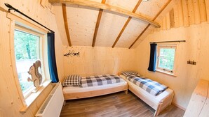 A cozy wooden cabin with two single beds, a radiator, and a window with a squirrel decoration. - Boshuis Dora met Escapespel | Recreatiepark  d`n Mastendol (Rijen)