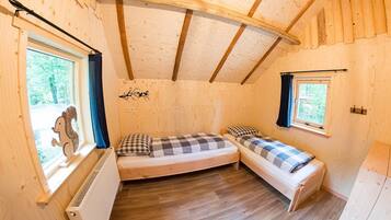 Een knus houten vakantiehuisje met twee eenpersoonsbedden, een radiator en een raam met een eekhoornbeeldje.
