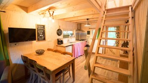 A wooden interior with a dining table, chairs, a kitchen area, and a ladder. - Boshuis Dora met Escapespel | Recreatiepark  d`n Mastendol (Rijen)