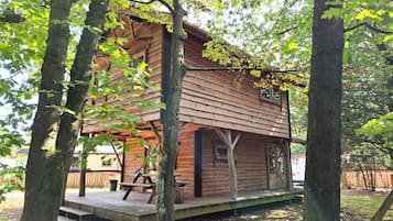 Een houten hutje met een veranda, omgeven door bomen.