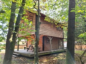 A wooden cabin with a porch, surrounded by trees. - Boshuis Dora | Gezinshuis met escapespel op d`n Mastendol | Rijen (Rijen)