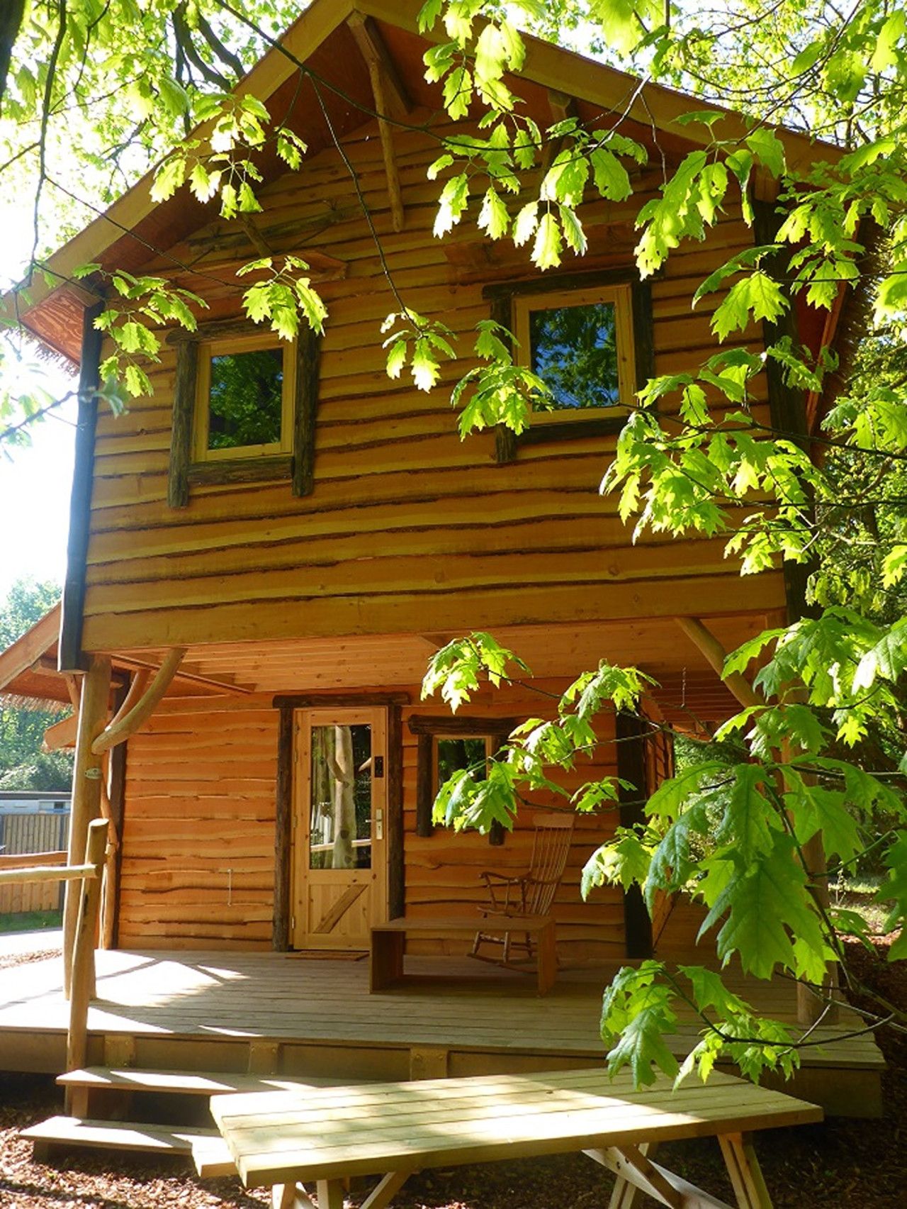 A wooden cabin with a porch, a door, and a window.