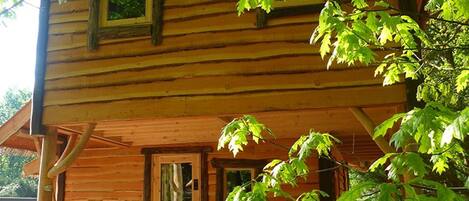 A wooden cabin with a porch, a door, and a window.