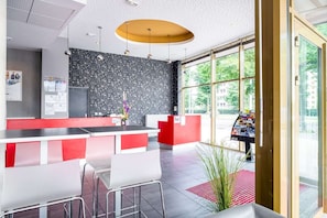A modern reception area with a bar, seating, and a large window offering a view of the outdoors.