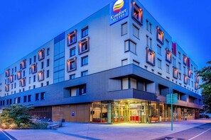 A multi-story hotel with a modern design, featuring a prominent Comfort Suites logo.