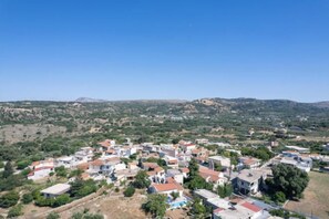 A residential area with houses, some with red roofs, and a hilly landscape in the background. - Silver Gem Villa with Private Pool (Frantzeskiana Metochia)