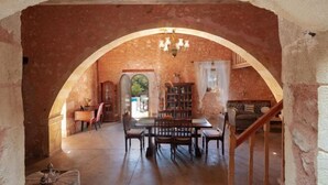 A dining area with a stone archway, a chandelier, and a staircase leading to another level. - Silver Gem Villa with Private Pool (Frantzeskiana Metochia)