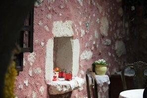 A rustic interior with a stone wall, a small alcove with candles, and a chair. - Silver Gem Villa with Private Pool (Frantzeskiana Metochia)