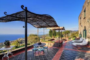 An outdoor patio with a table and chairs, a pergola, and a view of the sea. - Villa Fondo Turiello – Pool & Scenic View (Massa Lubrense)