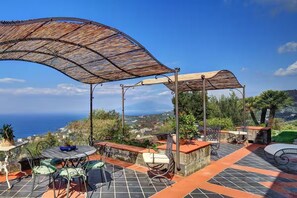 An outdoor patio with a table and chairs, a pergola, and a view of the sea. - Villa Fondo Turiello – Pool & Scenic View (Massa Lubrense)