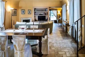 A dining area with a table set for four, a sofa, a fireplace, and a bookshelf.
