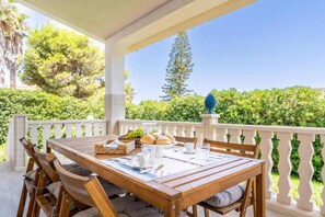 A wooden table set for breakfast with a view of greenery and a white balustrade. - Villa delle Lantane - Marzamemi, 70 mt beach (Noto)
