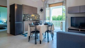 Une cuisine moderne équipée d’un réfrigérateur encastré, d’une table à manger avec des chaises et d’un téléviseur dans l’espace salon.