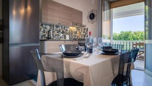 Une cuisine moderne dotée d’un réfrigérateur encastré, d’une table à manger pour quatre personnes et offrant une vue sur la verdure environnante.