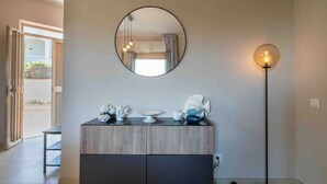 Une chambre moderne avec un meuble en bois, un miroir rond et un lampadaire.
