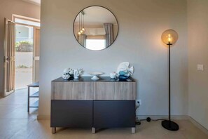 A modern room with a wooden cabinet, a round mirror, and a floor lamp. - Villa delle Lantane - Marzamemi, 70 mt beach (Noto)