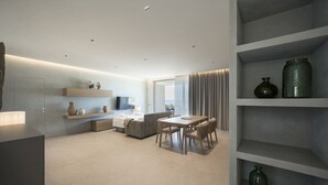 A modern interior with a dining area, sofa, and built-in shelves. - Cala Theresia, Alea - Sea front apartment (Pachino)