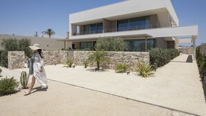 A modern building with a flat roof, large windows, and a stone wall. - Cala Theresia, Alea - Sea front apartment (Pachino)