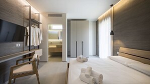 A modern hotel room with a bed, a TV, a desk, and a bathroom visible through an open door. - Cala Theresia, Alea - Sea front apartment (Pachino)
