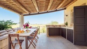 An outdoor patio with a wooden table, chairs, and a built-in grill. - Casa Degli Aromi - San Lorenzo, Noto (Noto)