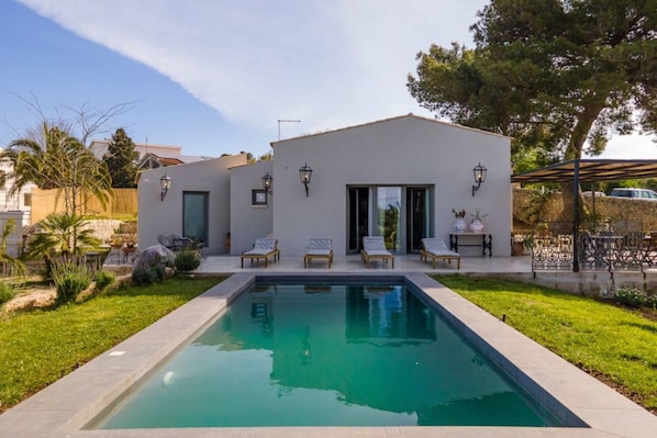 A modern house with a swimming pool, outdoor seating, and a well-maintained garden.