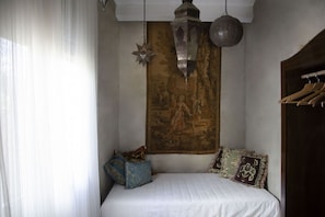 A bedroom with a bed, a tapestry, and a hanging lantern.