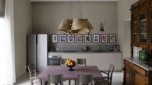 Une cuisine moderne avec un coin repas, comprenant un îlot central, des luminaires suspendus et des œuvres d’art encadrées accrochées au mur.