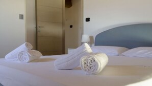 Habitación de hotel con una cama bien hecha, una lámpara en la mesita de noche y una puerta al fondo.