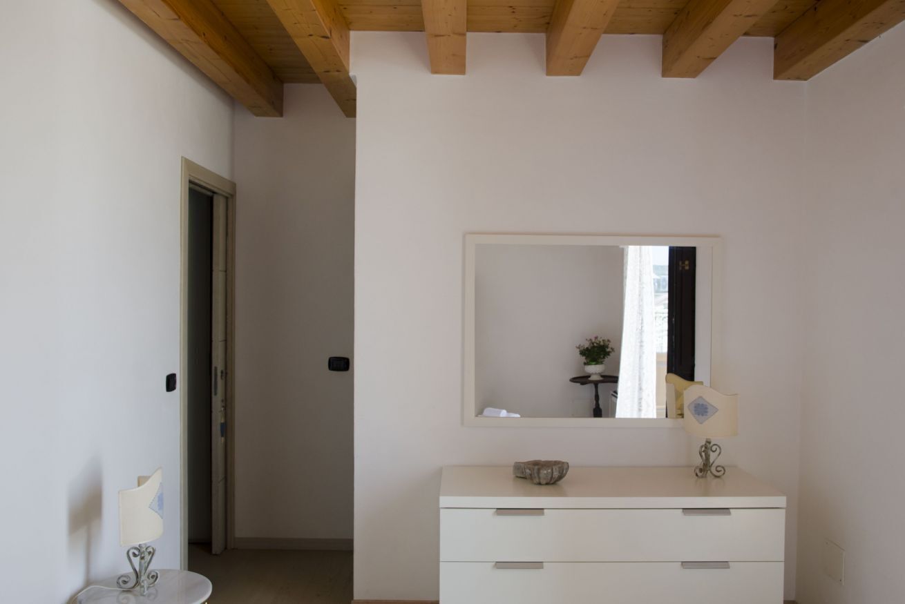 Un baño minimalista con un tocador blanco, un espejo y una puerta que da a otra habitación.
