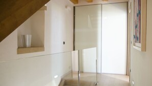 Un interior moderno con barandilla de vidrio, techo de madera y puerta corredera.