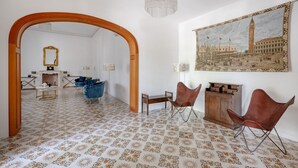 Una stanza con pavimento a motivi, un arco in legno, un quadro che raffigura una città e due poltrone in pelle.