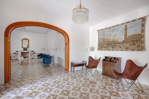Una habitación con piso estampado, un arco de madera, un cuadro de un paisaje urbano y dos sillones de cuero.