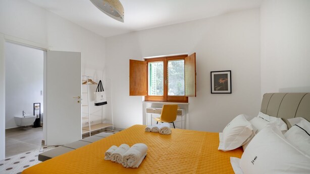 Una camera d'albergo con un letto, una finestra, una sedia e una scrivania.