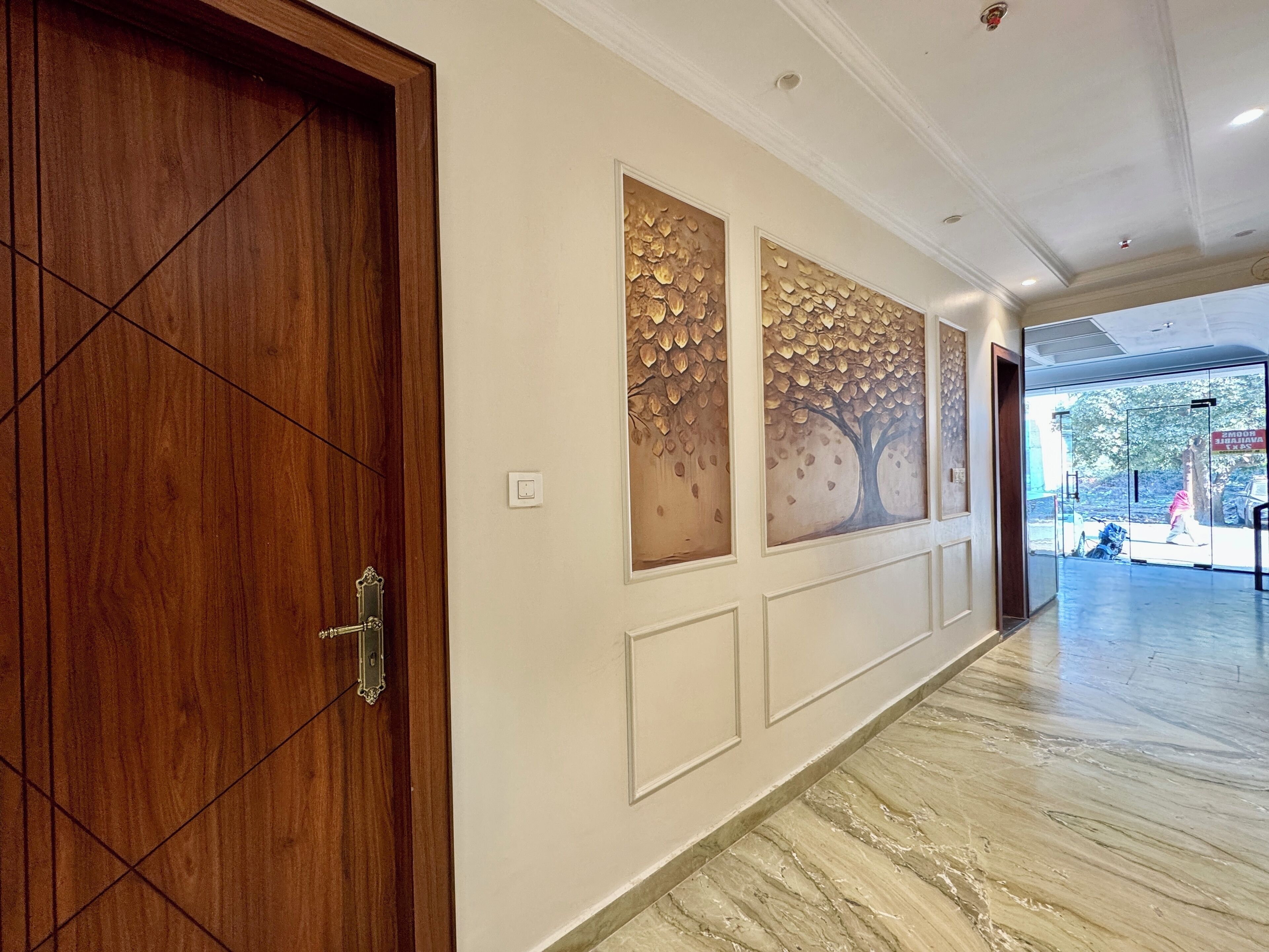 A hallway with a wooden door, decorative wall panels, and a marble floor.