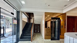 Een hotellobby met een marmeren vloer, een trap en een receptie.