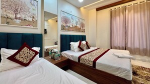 Een hotelkamer met twee bedden, een houten hoofdeinde, een nachtkastje met waterflessen en kunst aan de muren.