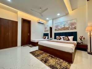 A bedroom with a large bed, a wardrobe, a ceiling fan, and artwork on the walls.