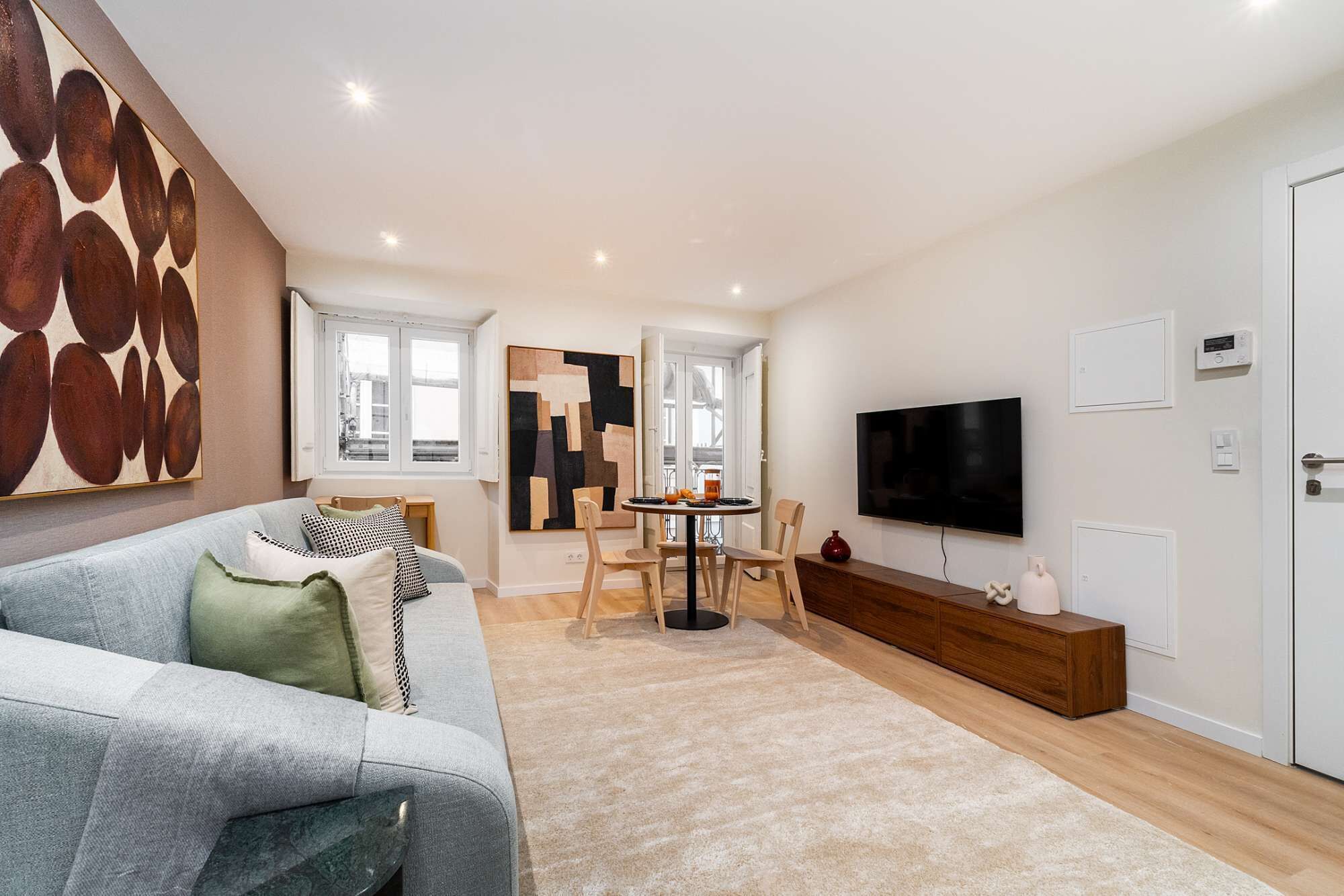 A modern living room with a grey sofa, a coffee table, and a TV mounted on the wall.