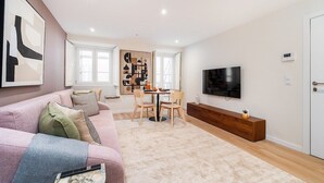 A modern living room with a sofa, coffee table, and a dining area with chairs and a table. - Live Lisbon from the Famous Green Street (Lisbon)